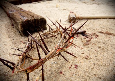easter scene with crown of thorns, hammer and nails with blood on sand